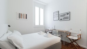 Camera da letto minimalista con un letto, una scrivania e due sedie.