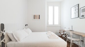 Una camera da letto minimalista con un letto, una scrivania e una finestra.