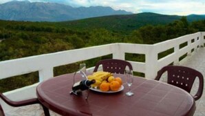 Une table avec une assiette de fruits et un verre d’eau, donnant sur un paysage montagneux.