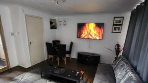 Un salon moderne avec un canapé, une table basse, un téléviseur fixé au mur et une cheminée.