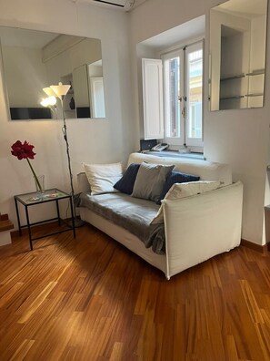 Ett modernt vardagsrum med en soffa, ett litet bord med en lampa och en stor spegel.