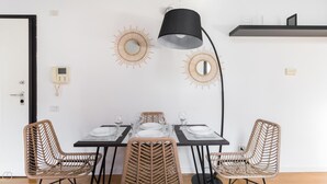 A dining area with a black table, wicker chairs, a black pendant lamp, and decorative sunburst mirrors on the wall. - Italianway Comfort - Salomone 51 (Milan)