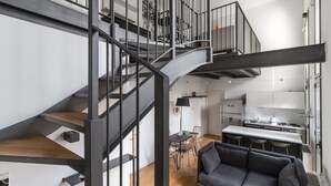 A modern apartment with a central spiral staircase, a dining area, and a kitchenette. - Italianway Comfort - Salomone 51 (Milan)