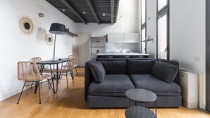 A modern living space with a sofa, dining table, chairs, and a kitchen area. - Italianway Comfort - Salomone 51 (Milan)