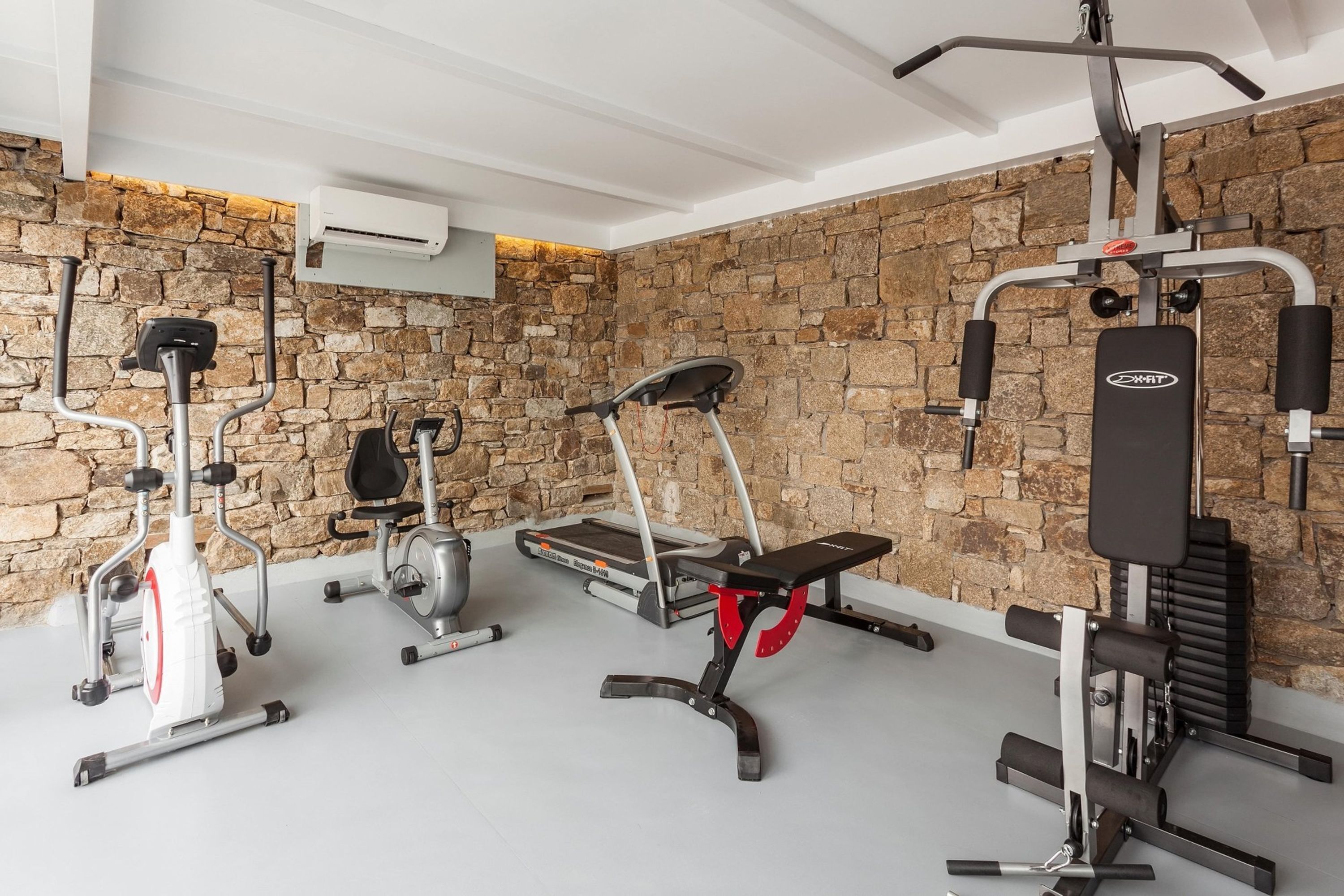 A gym with various exercise equipment including a treadmill, elliptical, and weight machines.