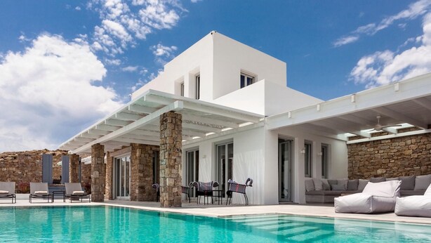 A modern villa with a swimming pool, stone pillars, and outdoor seating. - Epic Twin Luxurious 14 Bedrooms Villa for 28 (Mykonos)