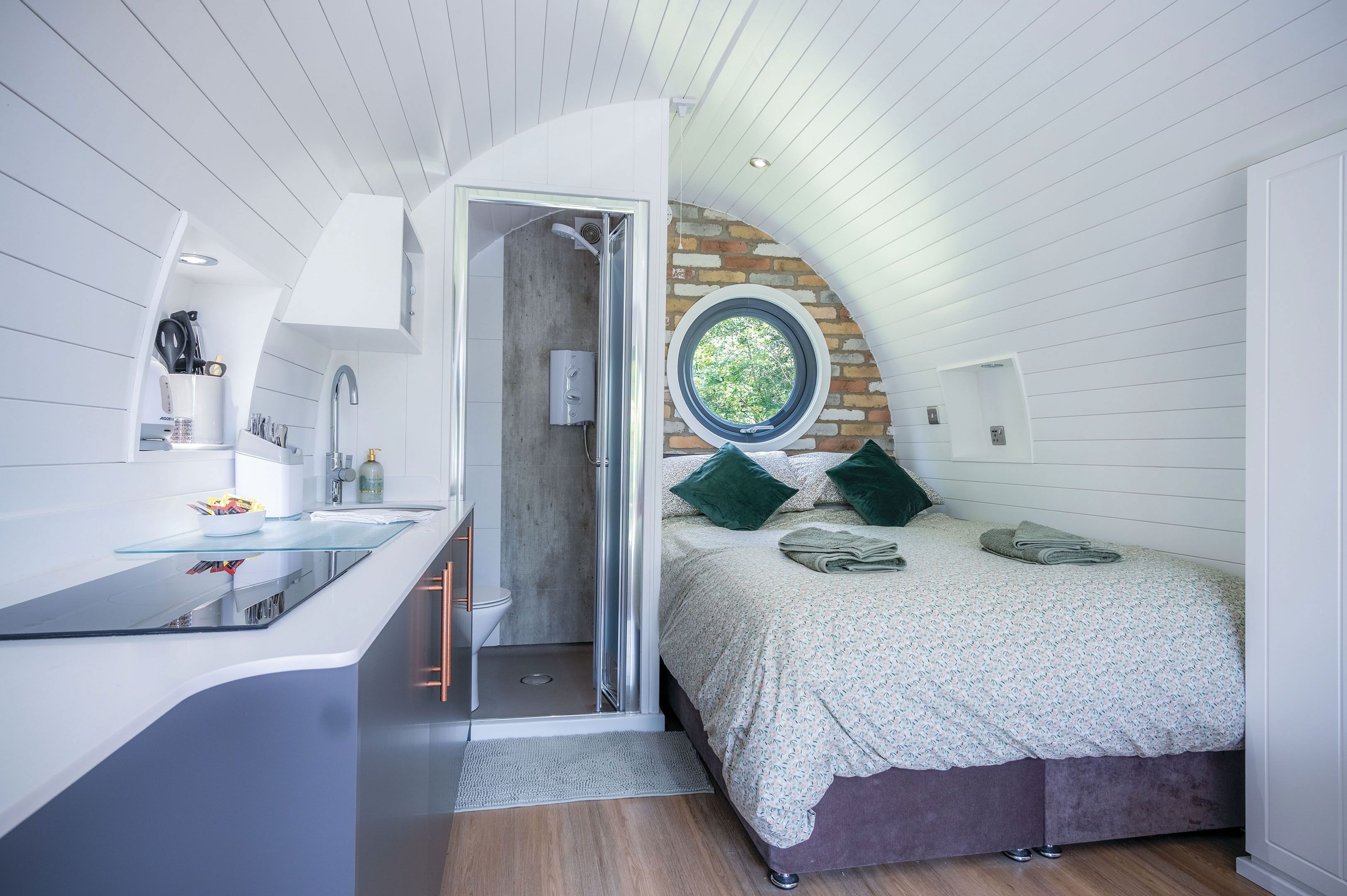 Une chambre moderne dotée d’une douche intégrée, d’un comptoir-bar en verre et d’une grande fenêtre.