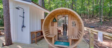 Relax in a serene forest setting, surrounded by nature, with a sauna and shower area nearby.