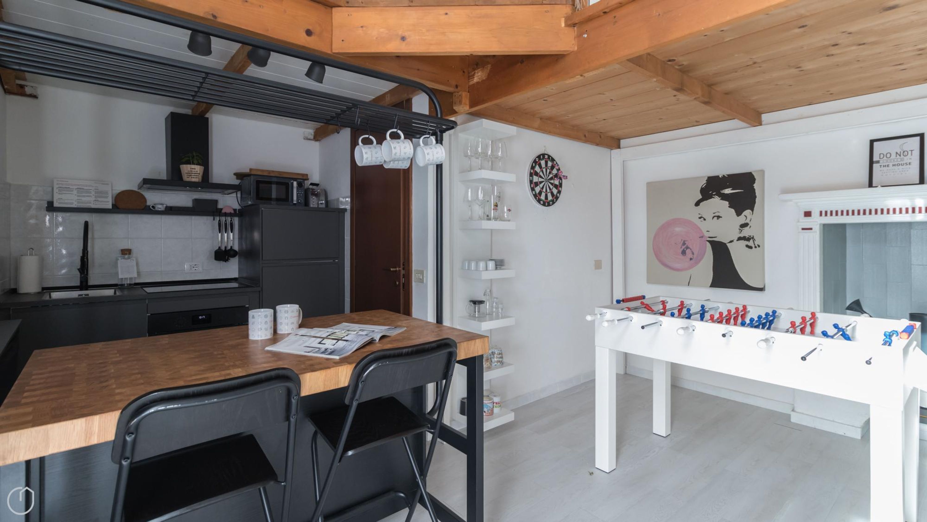 A modern kitchen with a wooden table, chairs, and a foosball table.