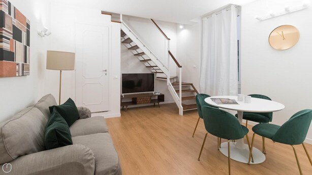 A modern living room with a sofa, a dining table with chairs, a TV, and a staircase. - Italianway Easy - Ripa Ticinese 17 B (Milan)