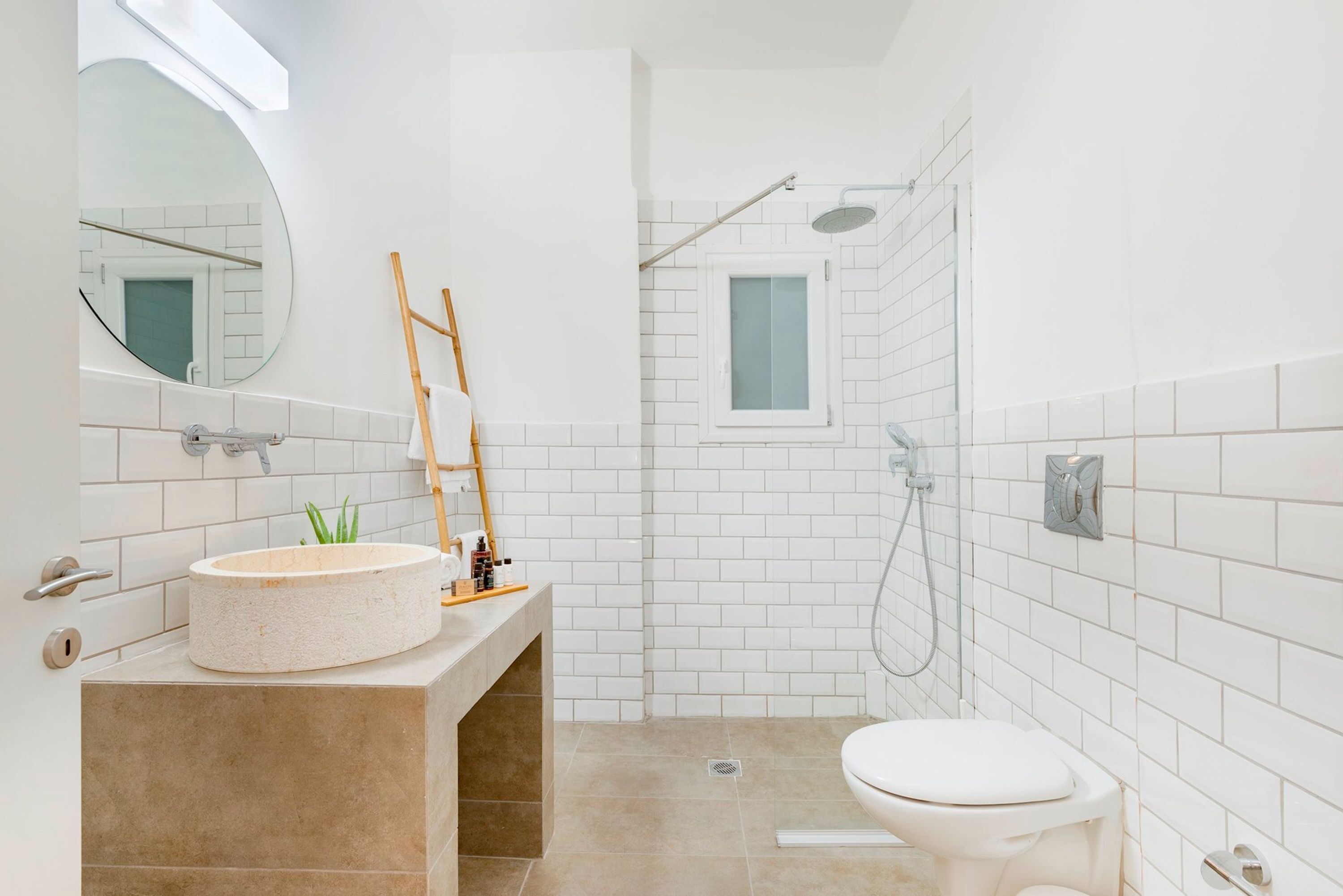 A modern bathroom with a round sink, a toilet, and a shower area.