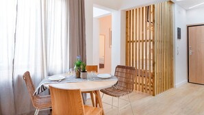 A dining area with a round table, two wicker chairs, a striped tablecloth, and a potted plant. - Premium Deluxe Apartment -c2-common Terrace (Piraeus)
