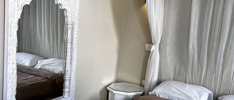 Un dormitorio con un espejo grande y ornamentado, una cama con cabecera marrón y una mesita de noche.