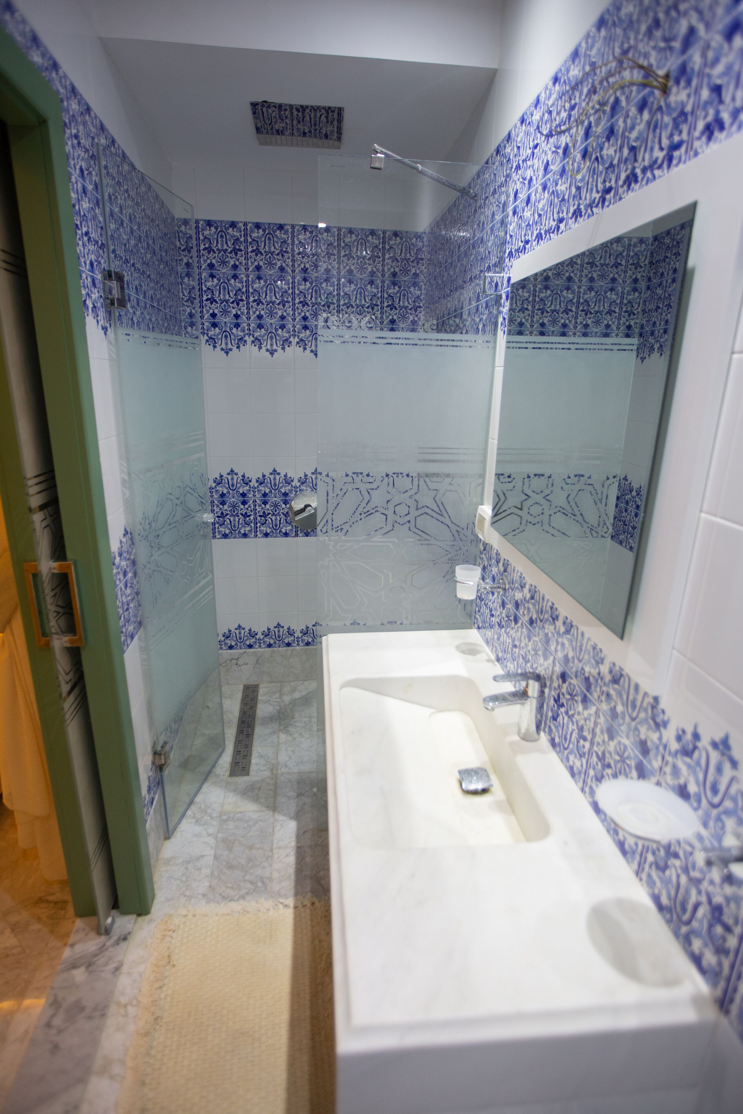 A bathroom with a white sink, a mirror, and blue patterned tiles.