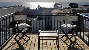 A wooden deck with two chairs and a small table, overlooking a body of water and buildings in the background. - Dar Hammamet Guest House & Hammam (Hammamet)