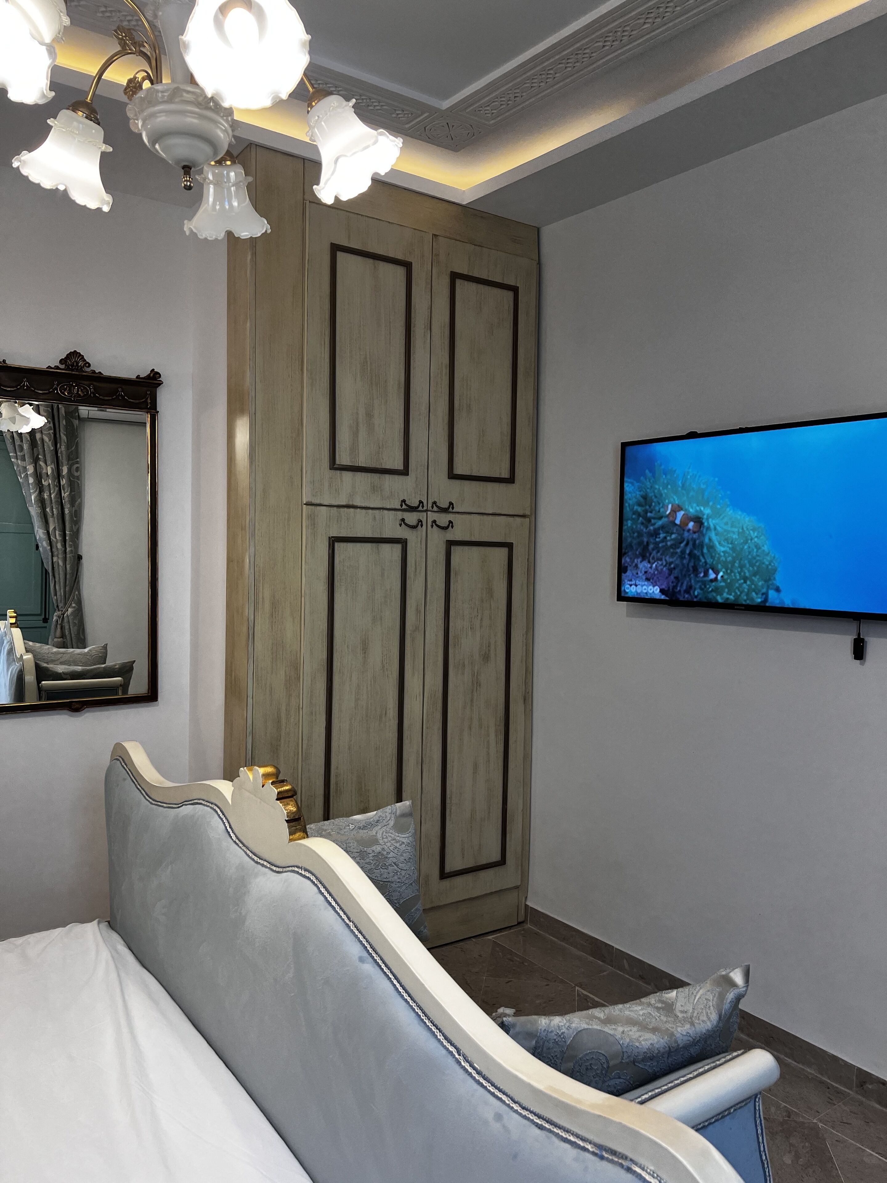 A bedroom with a bed, a television mounted on the wall, and a wardrobe.