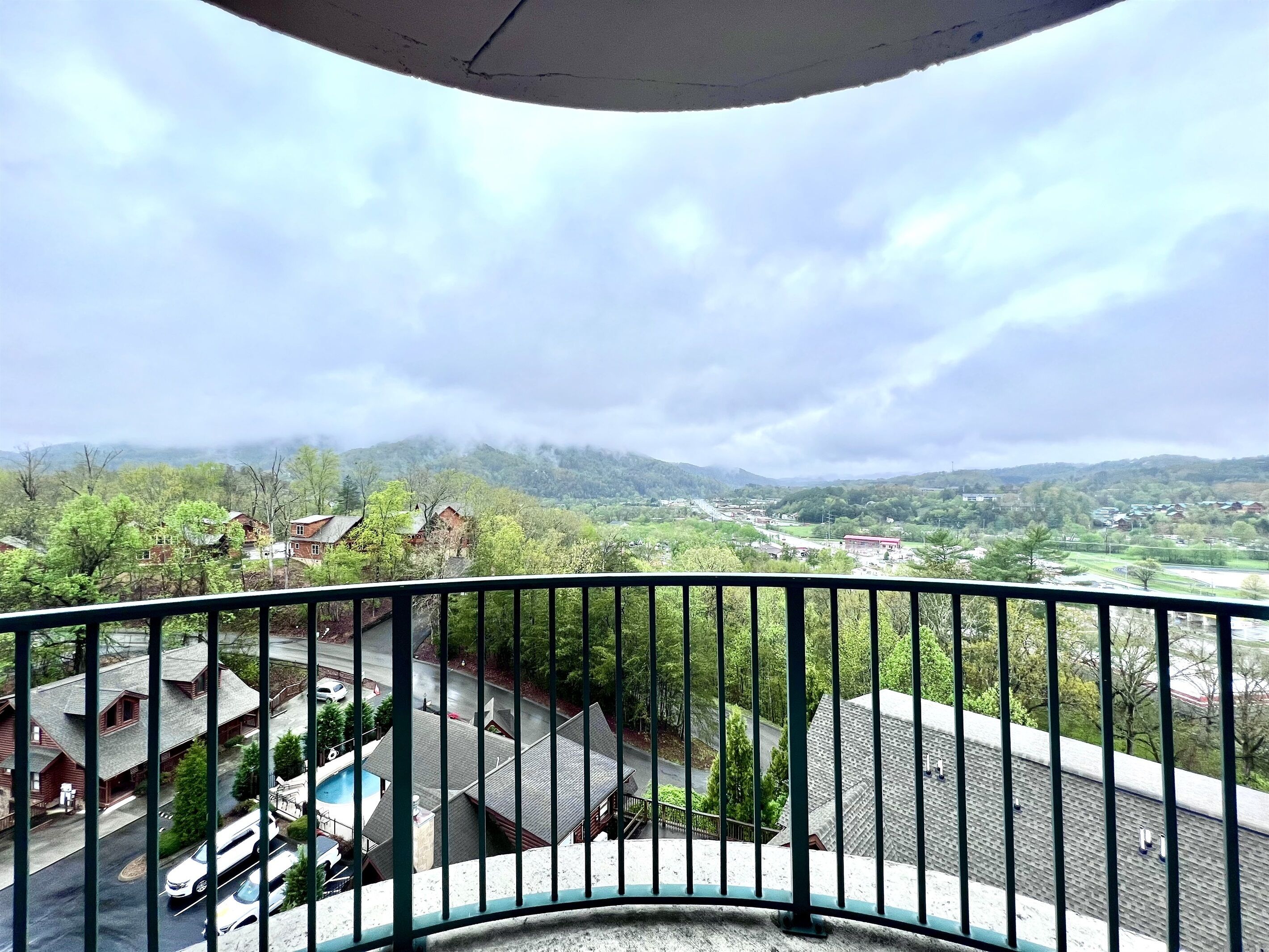 A balcony with a view of a residential area, including houses and a road.