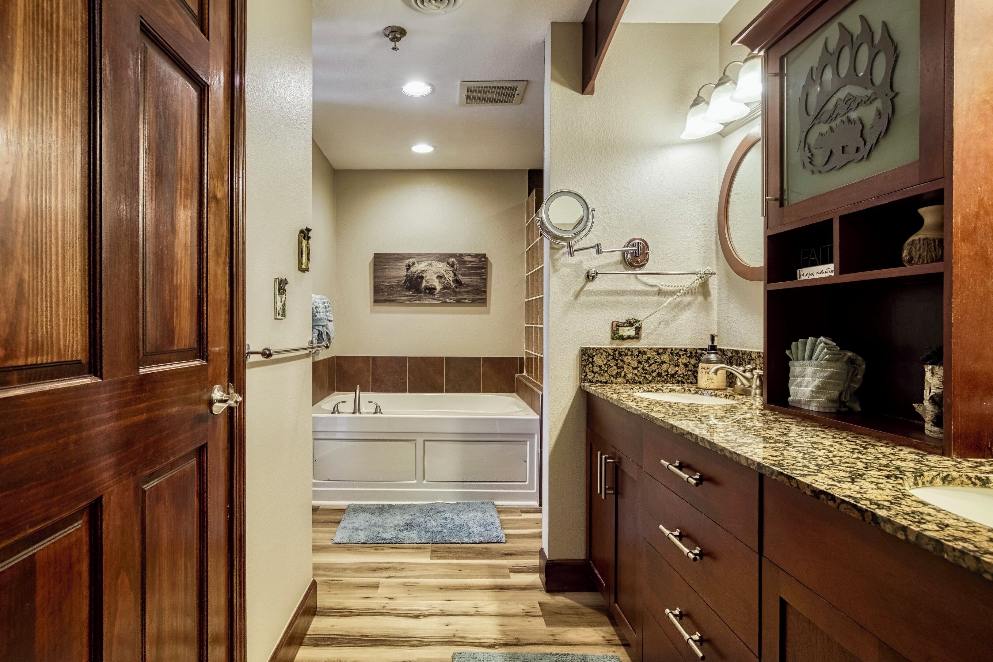 A bathroom with a wooden vanity, a bathtub, and a mirror.