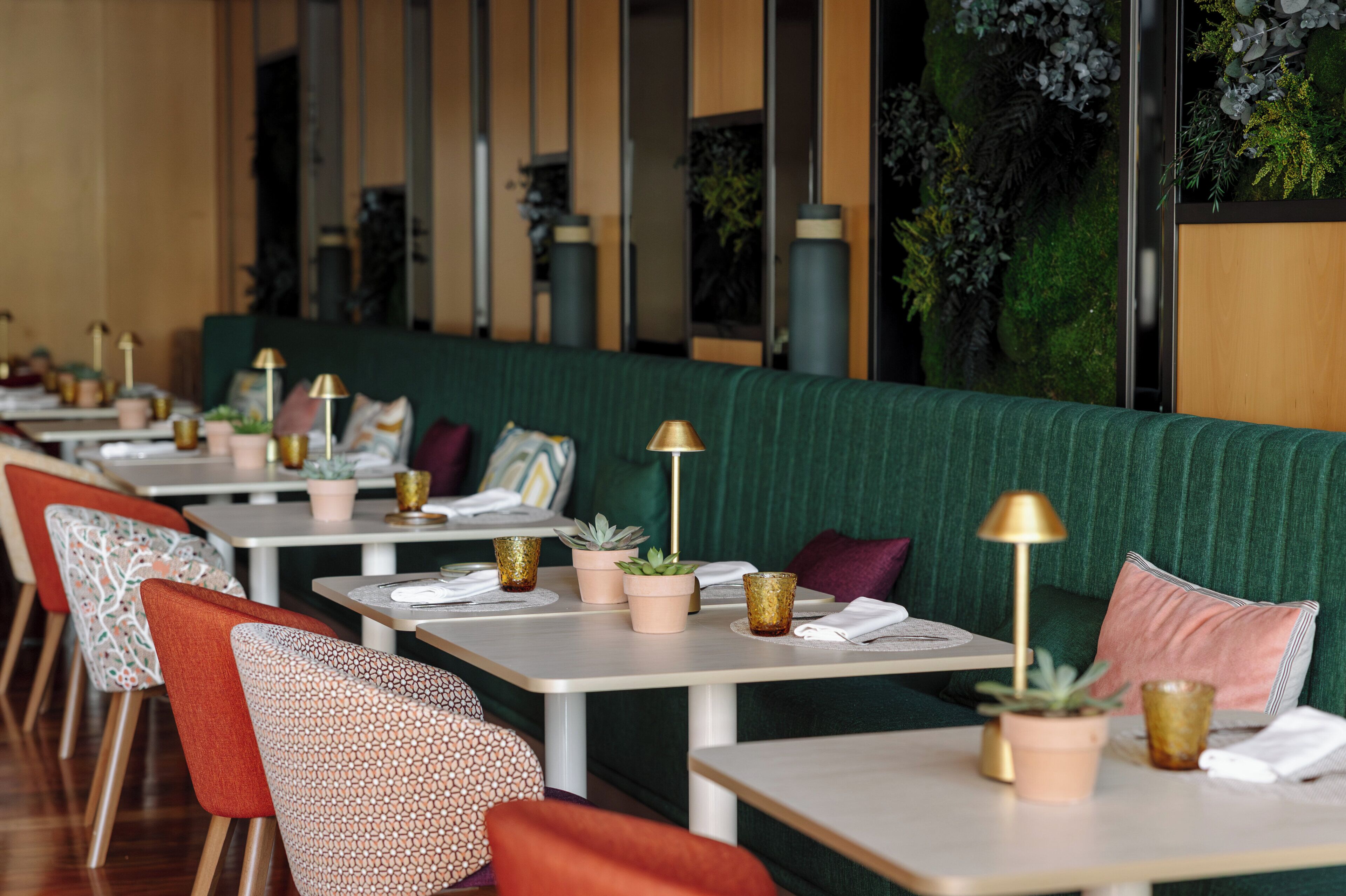 Un restaurante con cabinas, mesas y plantas en macetas.