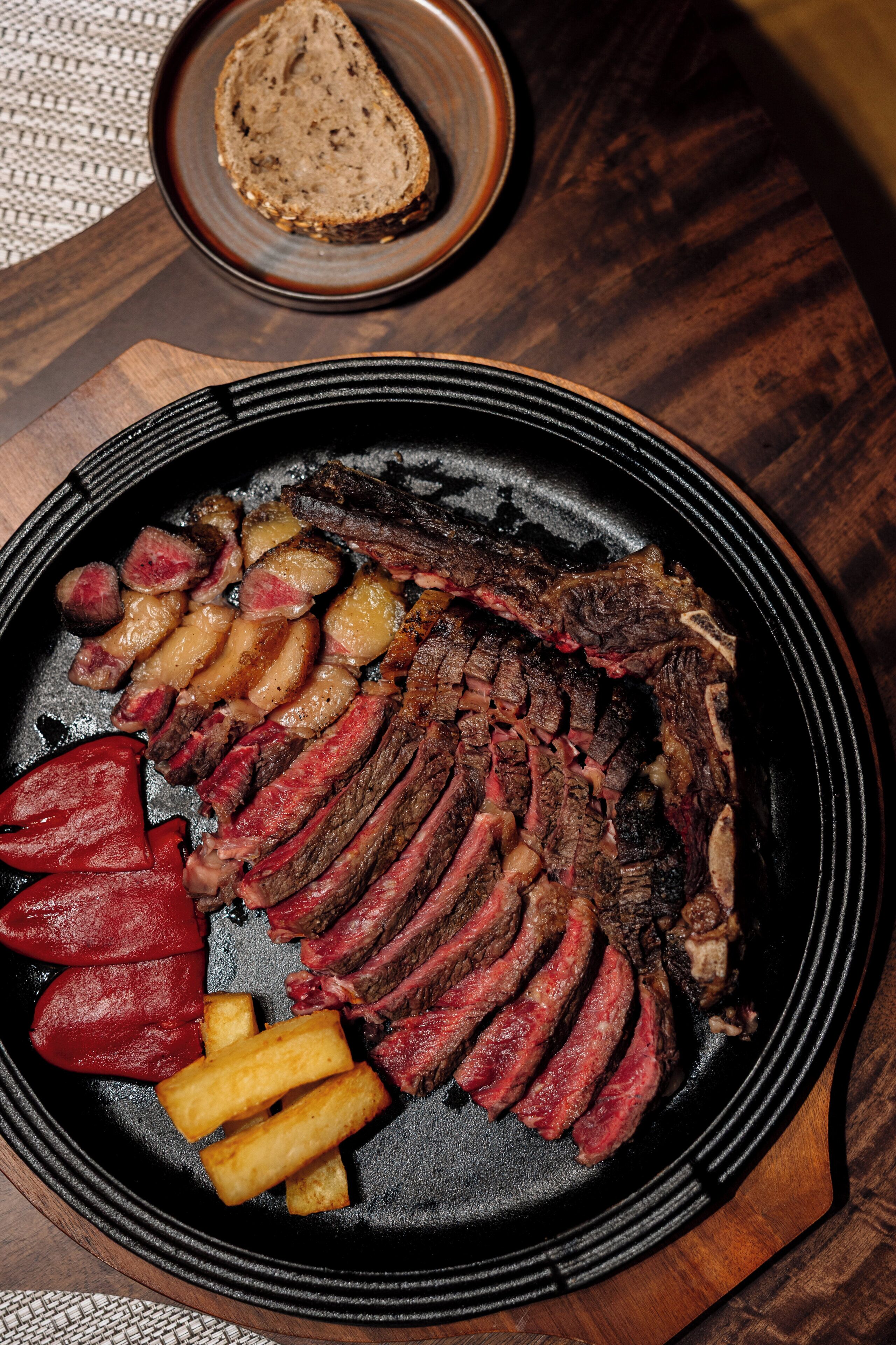 A steak, fries, and a slice of bread on a plate.