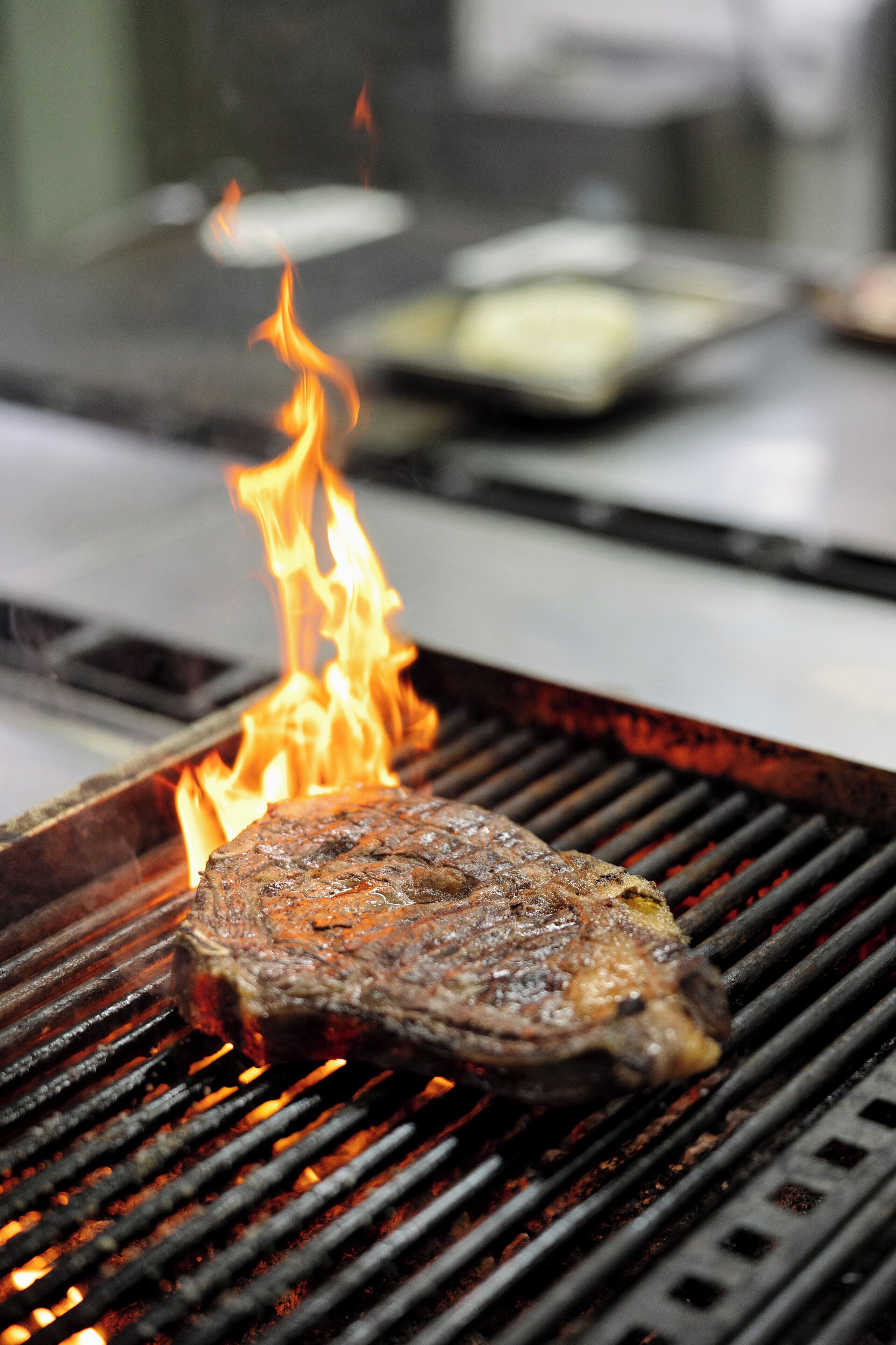 Un filete asándose en una parrilla, con llamas visibles.