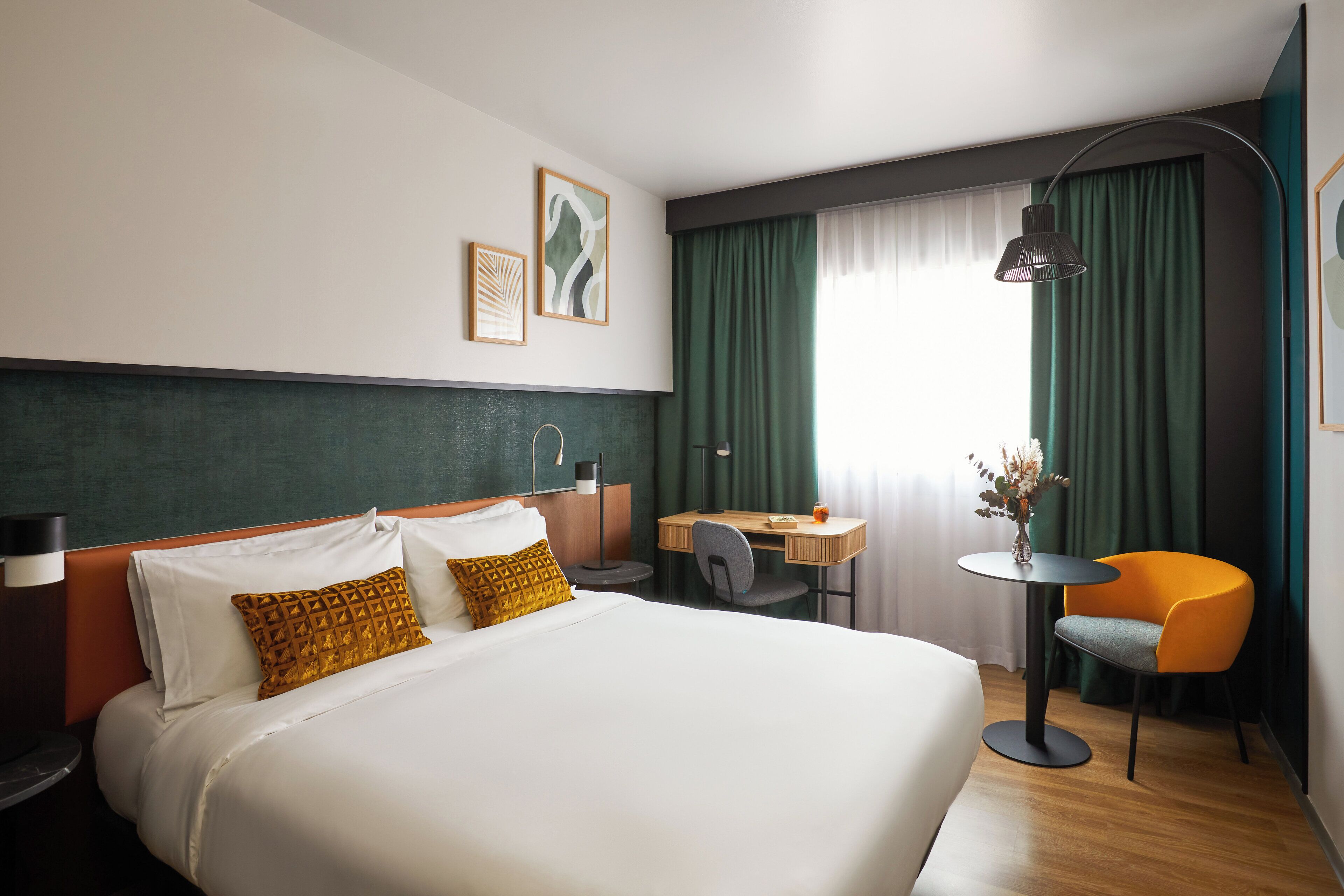 Habitación de hotel con una cama grande, un escritorio, una silla y una lámpara.