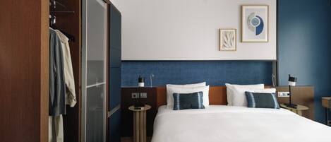A hotel room with a large bed, a wardrobe, a bedside table, and a nightstand.