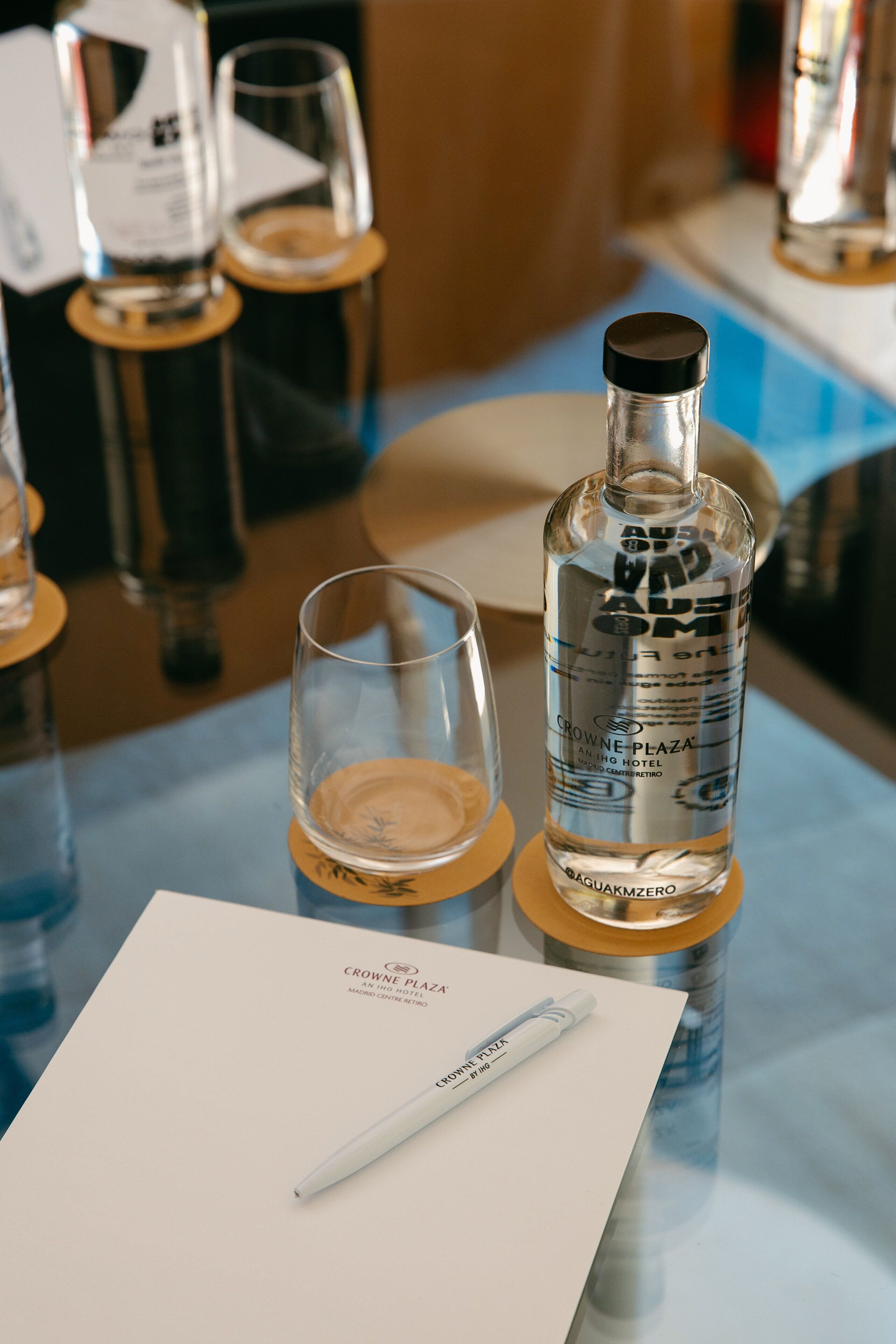 A bottle of Baquakmzero on a table with a glass and a pen.