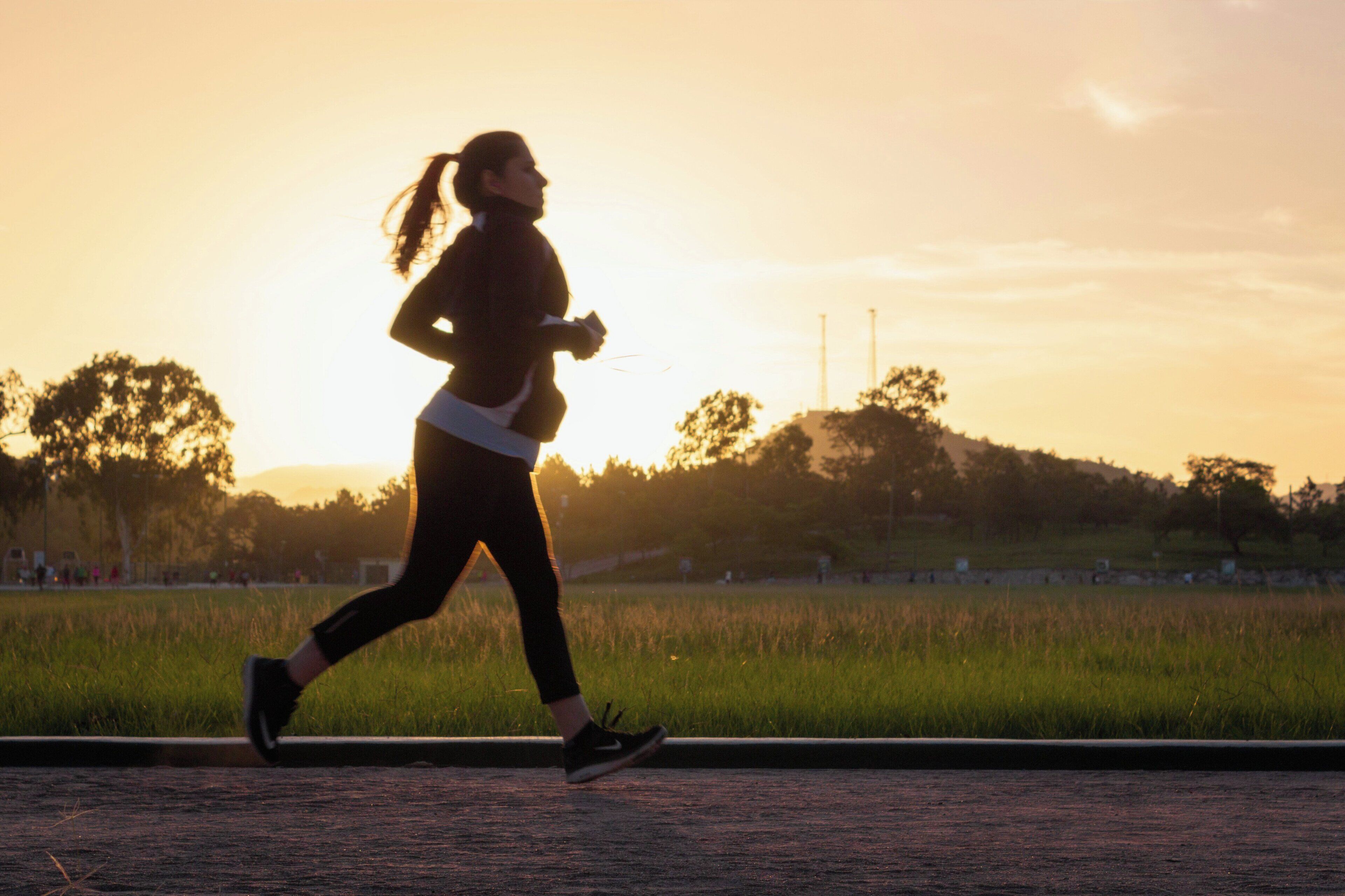 A person jogging on a path with a sunset in the background.