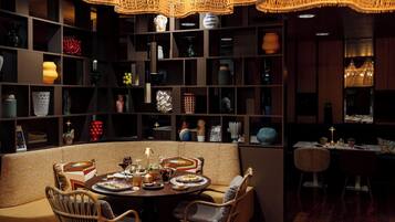 A dining area with a round table, chairs, and a bookshelf filled with various decorative items.