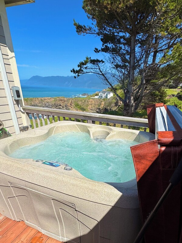 Ein Whirlpool auf einer Terrasse mit Blick auf das Meer und die Berge.