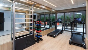 Una palestra moderna con tapis roulant, rastrelliera per pesi e parete a specchio.