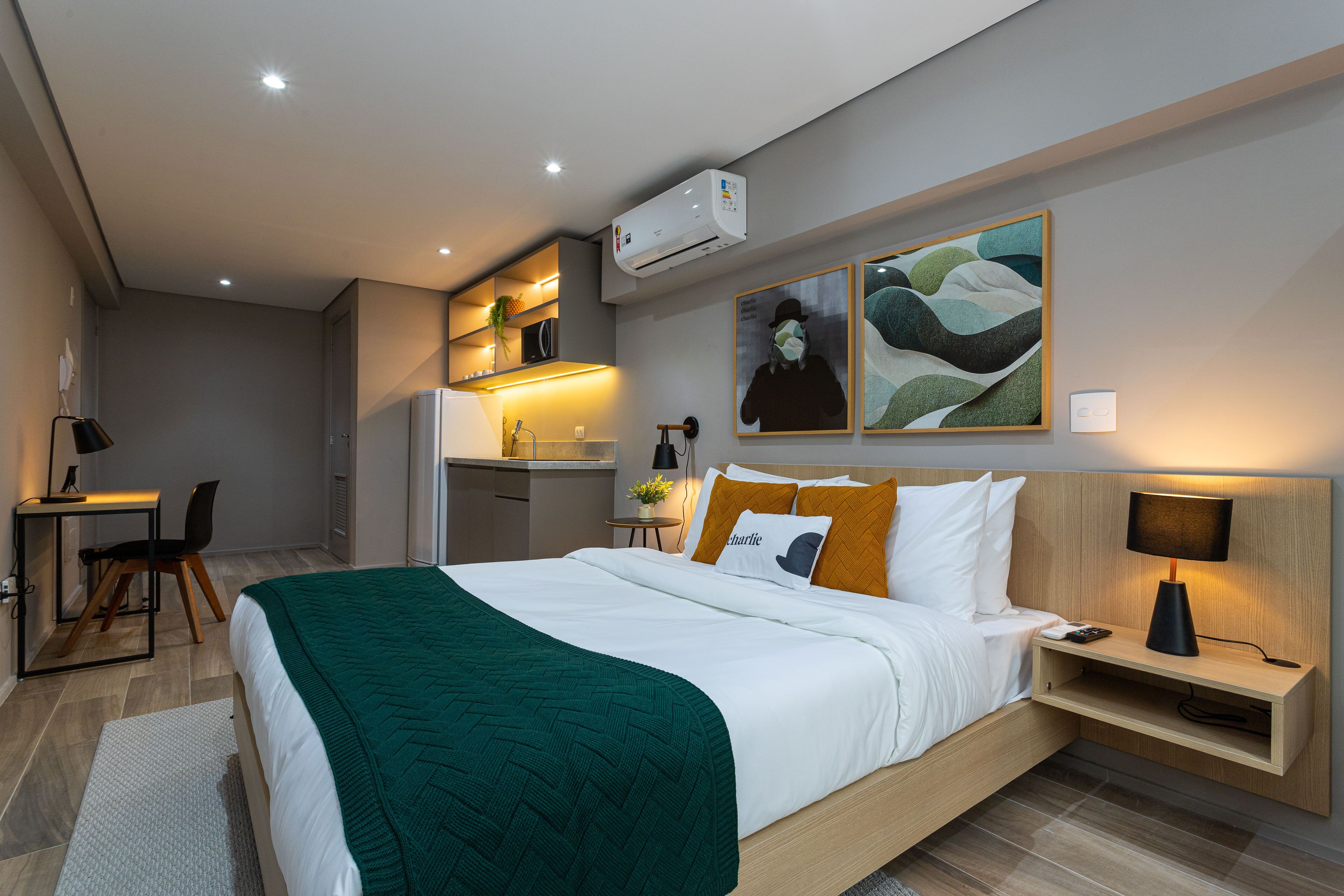 Una habitación de hotel moderna con una cama bien hecha, un escritorio y un rincón americano.