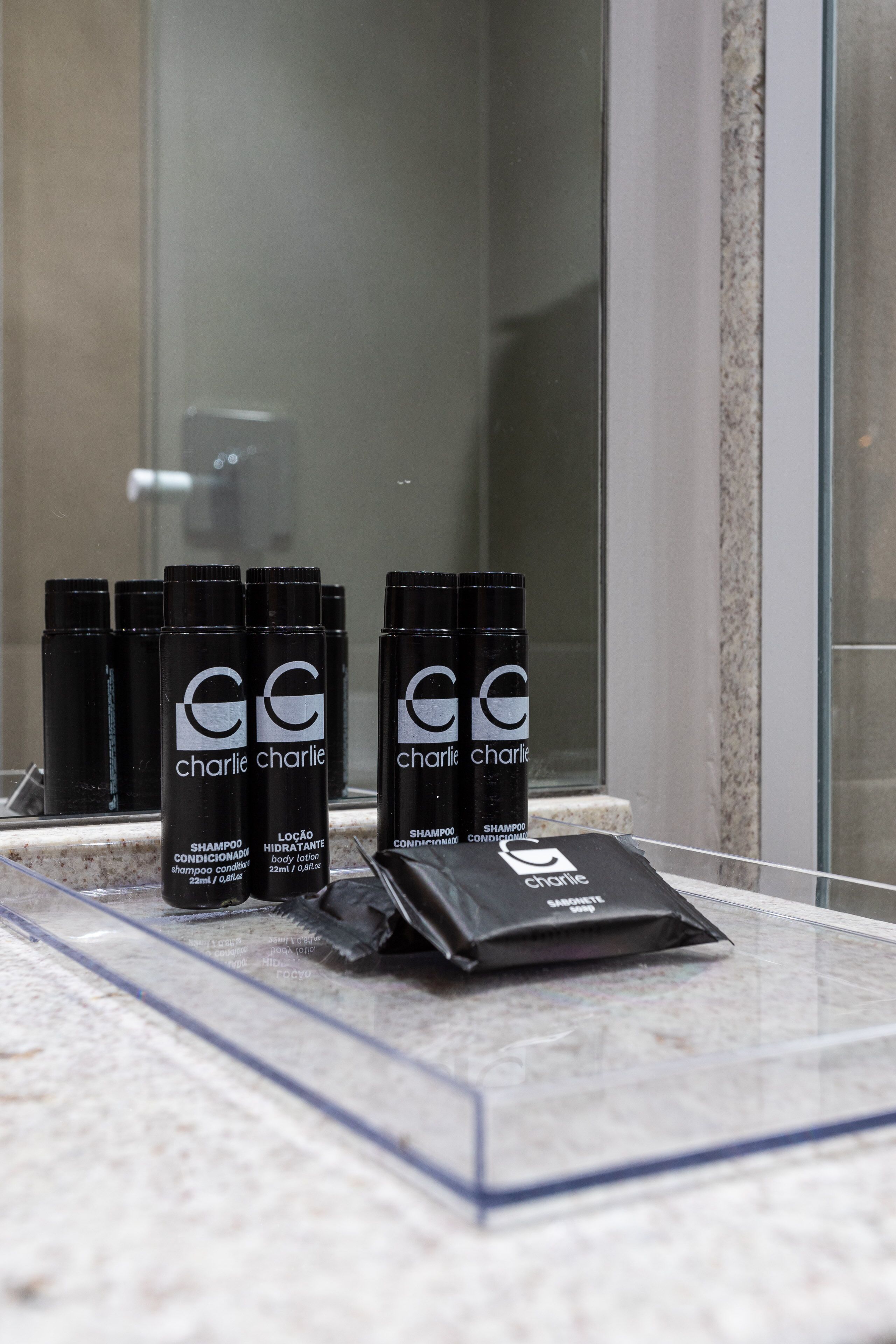 A bathroom counter with several bottles of Charlie Charlie body lotion and shampoo conditioner.