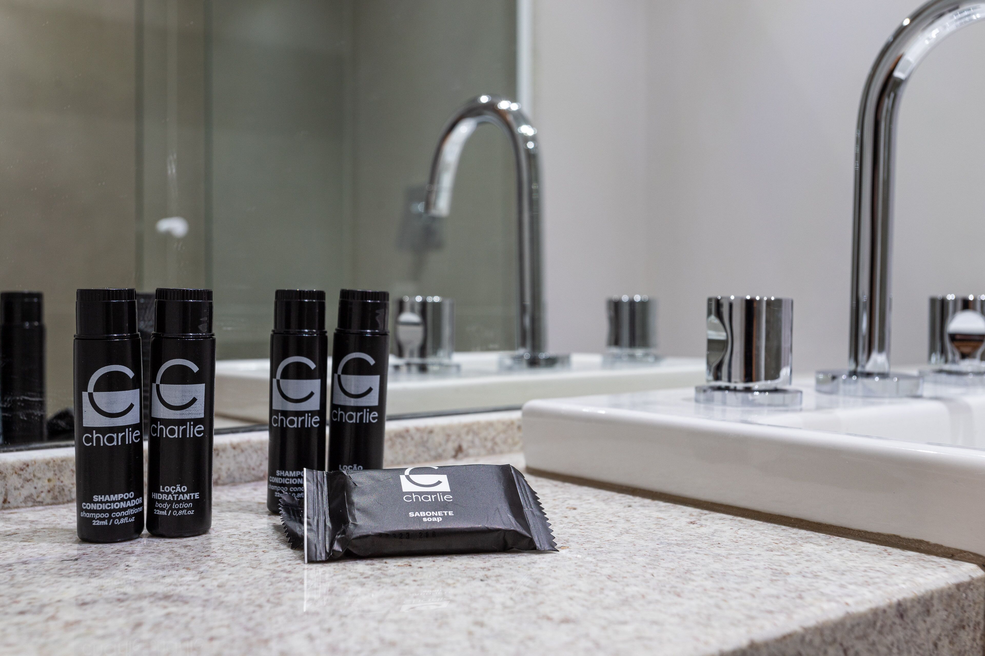 Una encimera de baño con artículos de aseo como champú, acondicionador, crema corporal y jabón.