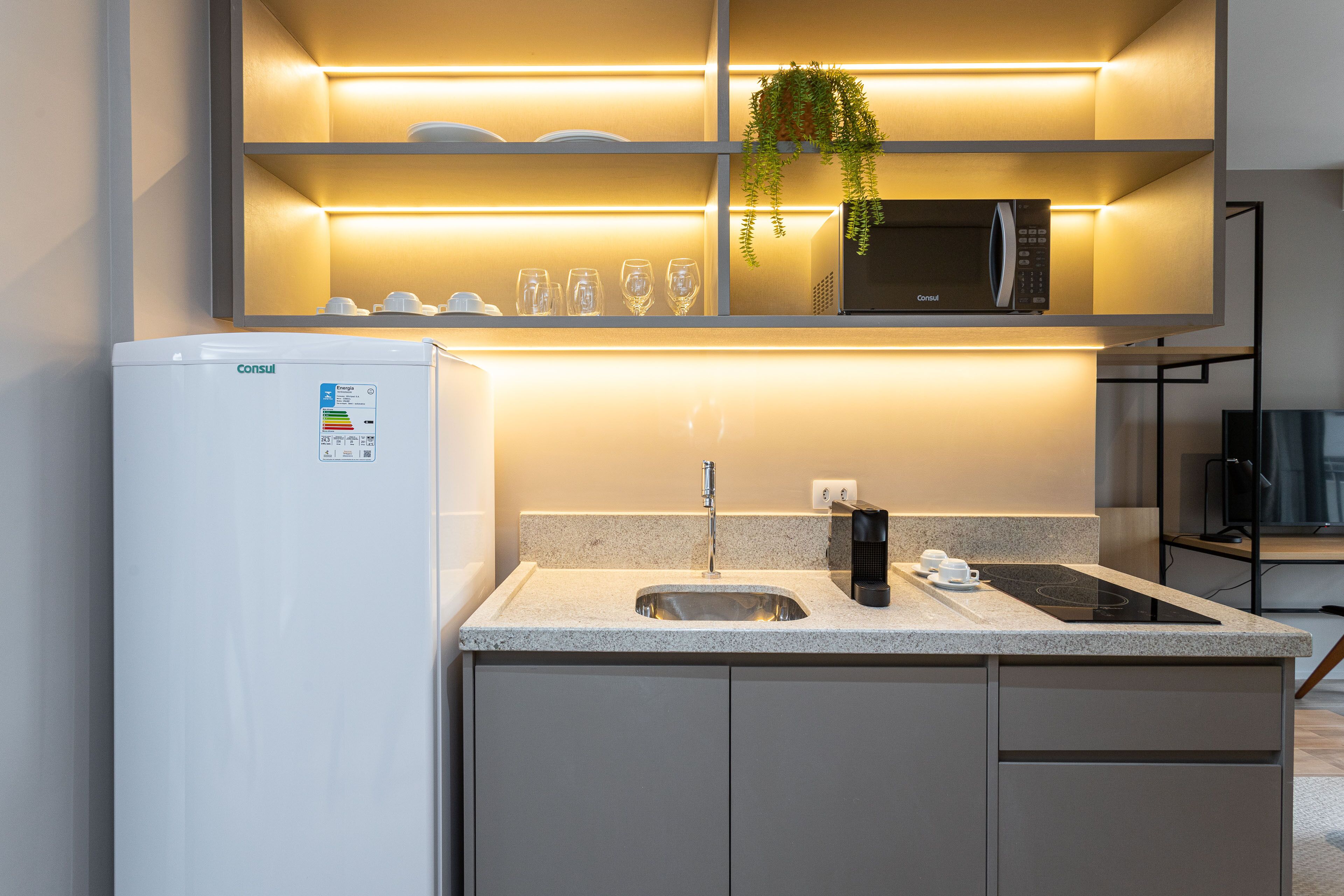 A modern kitchen with a built-in microwave, a sink, and a coffee maker.