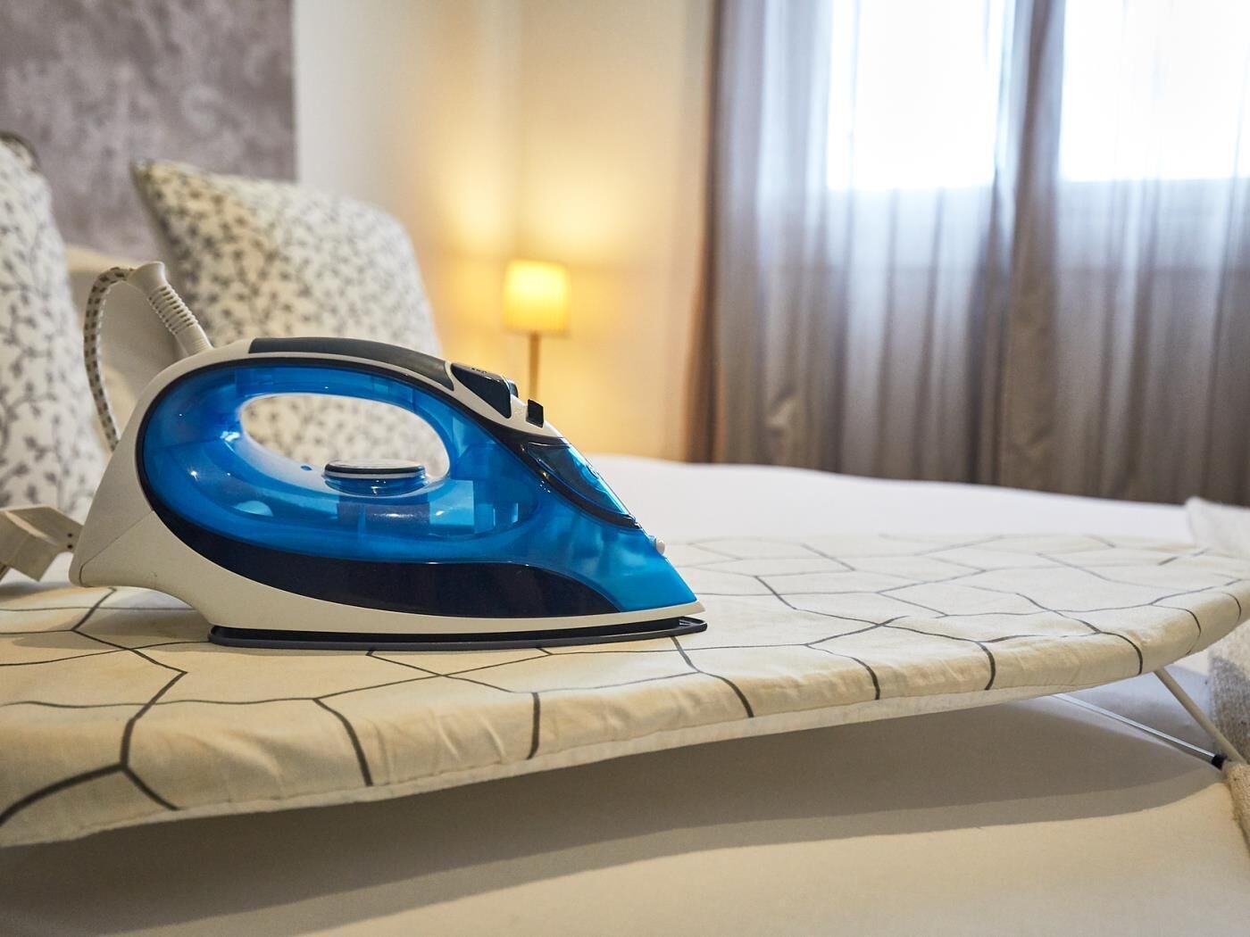 Una cama con un colchón blanco y un plancha azul sobre una tabla de planchar.