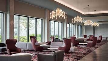 A hotel lobby with rows of seating, large windows, and chandeliers.