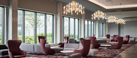 A hotel lobby with rows of seating, large windows, and chandeliers.