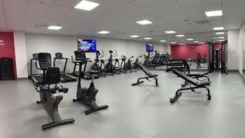 Een sportschool met diverse fitnessapparaten, waaronder loopbanden, hometrainers en krachttoestellen.