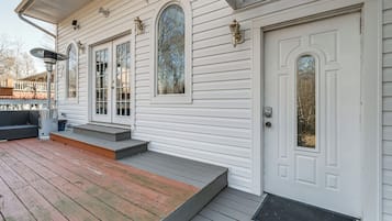 A white house with a front porch, a door with a glass panel, and a window with a view of trees.