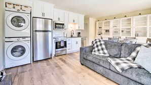Eine moderne Küche mit Edelstahlgeräten, einem grauen Sofa und einem Deckenventilator.