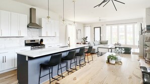 A modern kitchen with white cabinets, a central island with bar stools, and pendant lighting. - New! Downtown, Rooftop, Walkable to The Gulch, Music Row & 1M to Broadway! (Nashville)
