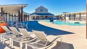 A pool area with lounge chairs and a covered seating area. - A Block from the Dock in Beau Coast Classic (Beaufort)