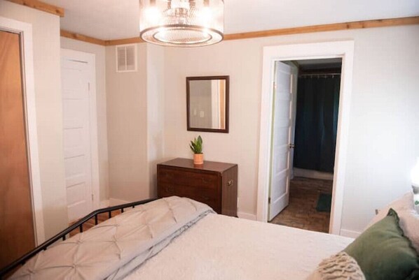 A bedroom with a bed, a dresser, a mirror, and a door leading to a closet. - The Refuge at Laurel (Shipman)