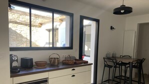 A kitchen with a built-in oven, a coffee maker, and a toaster. There is a window with a view of a stone building outside.