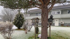 A two-story building with a balcony, a birdhouse on a tree, and a stone wall. - Cozy apartment in Gol with WiFi (Gol)