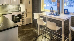 A modern kitchen with a built-in oven, a refrigerator, and a dining area with a table and chairs. - Cozy apartment in Gol with WiFi (Gol)