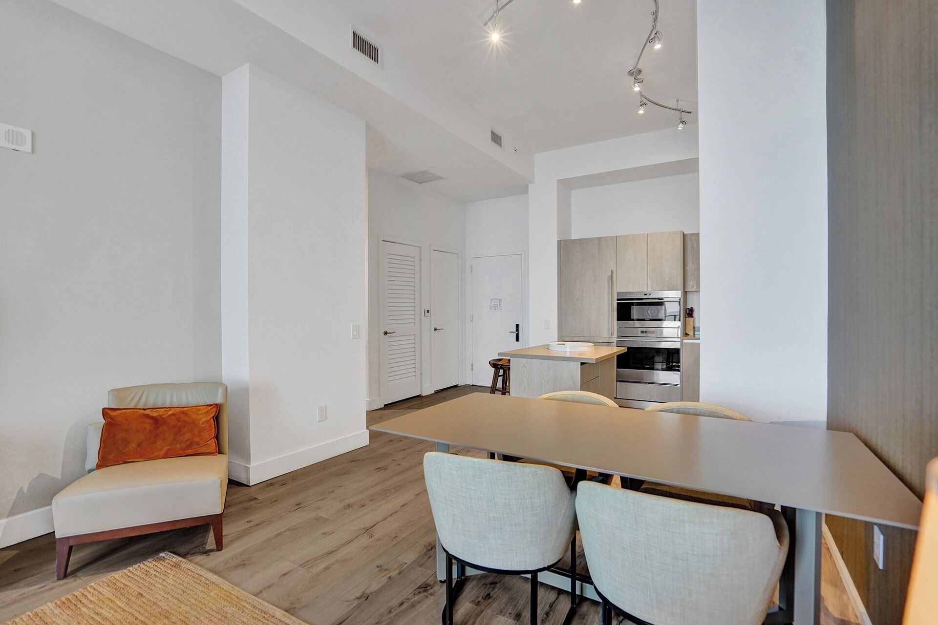 A modern apartment with a dining area, a kitchen, and a living space.