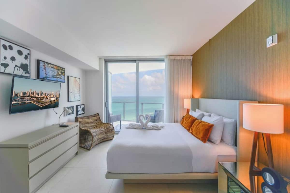 Une chambre d’hôtel avec un grand lit, une télévision, un bureau et une vue sur l’océan.
